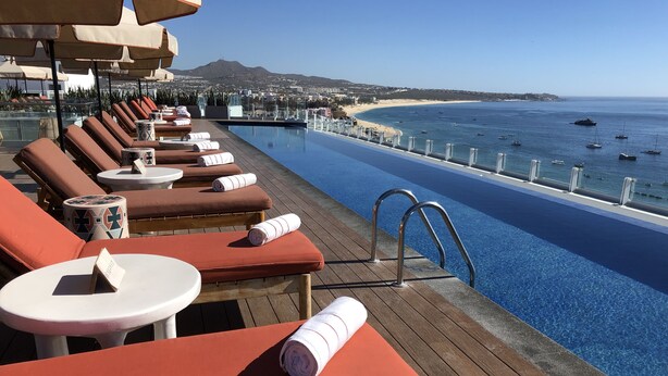 A poolside area with lounge chairs and a view of the ocean.