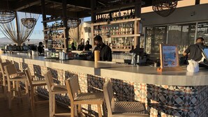 A bar area with a counter, bar stools, and shelves of bottles.