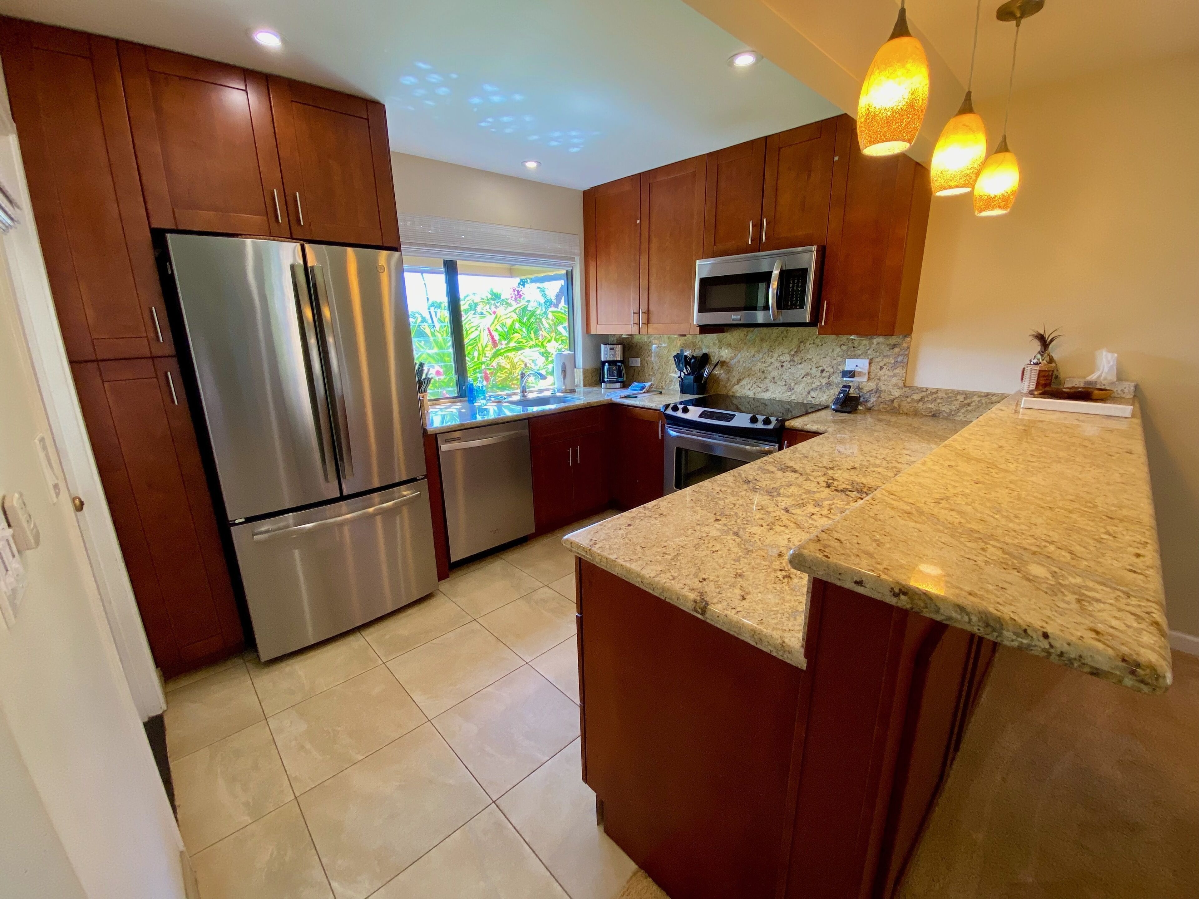 A modern kitchen with stainless steel appliances, granite countertops, and wooden cabinets.