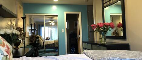 A hotel room with two beds, a mirror, a vase with flowers, and a ceiling fan.