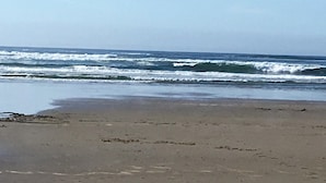 A beach with waves approaching the shore. - NEW! Tranquil Oceanfront Gem with Hot-tub 3 BDRM + Den, 3 BATH (Waldport)