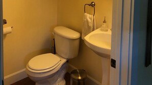 Een kleine badkamer met toilet, wastafel en kast.