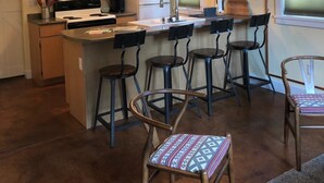 Een keuken met houten kastjes, een magnetron, een koelkast, een spoelbak en een bar met krukken.