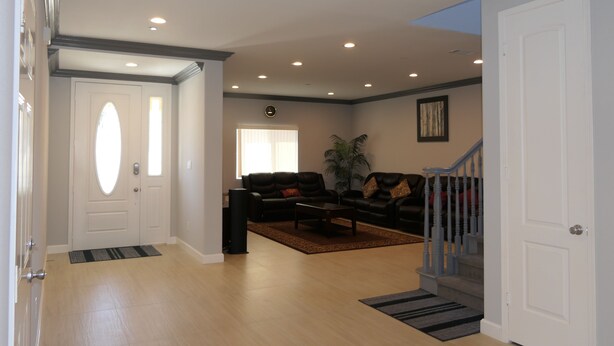 A spacious living room with a black leather sofa, a coffee table, and a large window. - * Living Large * Newly Built * Disneyland & Beaches (Midway City)