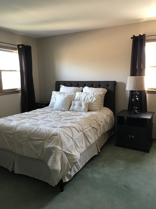 A neatly made bed with a tufted headboard, a bedside lamp, and a nightstand.