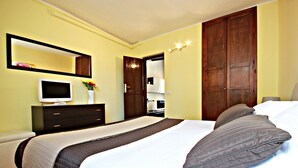 Hotellihuone, jossa on sänky, televisio, lipasto ja vaatekaappi.