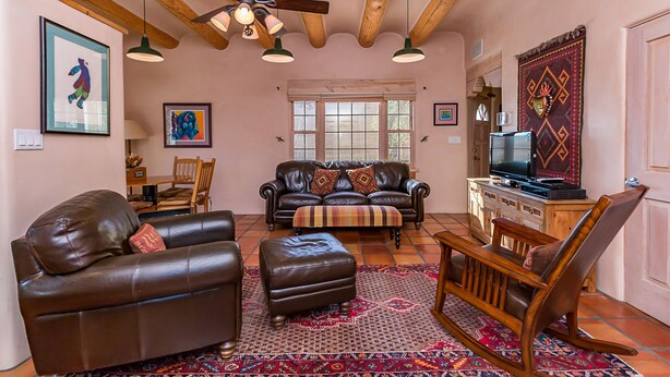 A cozy living room with a leather sofa, ottoman, wooden rocking chair, and a television on a wooden cabinet. - Favorite Downtown Adorable Adobe ~ 10 min walk to Plaza (Santa Fe)