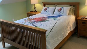 Un dormitorio con una cama de madera, una mesita de noche, una lámpara y un cuadro en la pared.