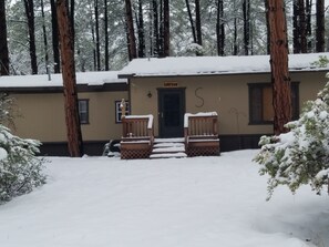 Escape to a serene cabin-style retreat surrounded by snow-covered trees and a peaceful forest.