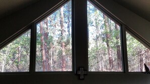 A room with a large window overlooking a forest. - Escape to Cool Twin Pines! (Pine)
