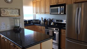 A kitchen with wooden cabinets, a stainless steel refrigerator, a microwave, a stove, and a coffee maker.