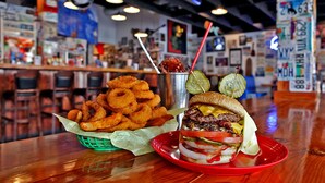A burger and onion rings on a table in a restaurant.