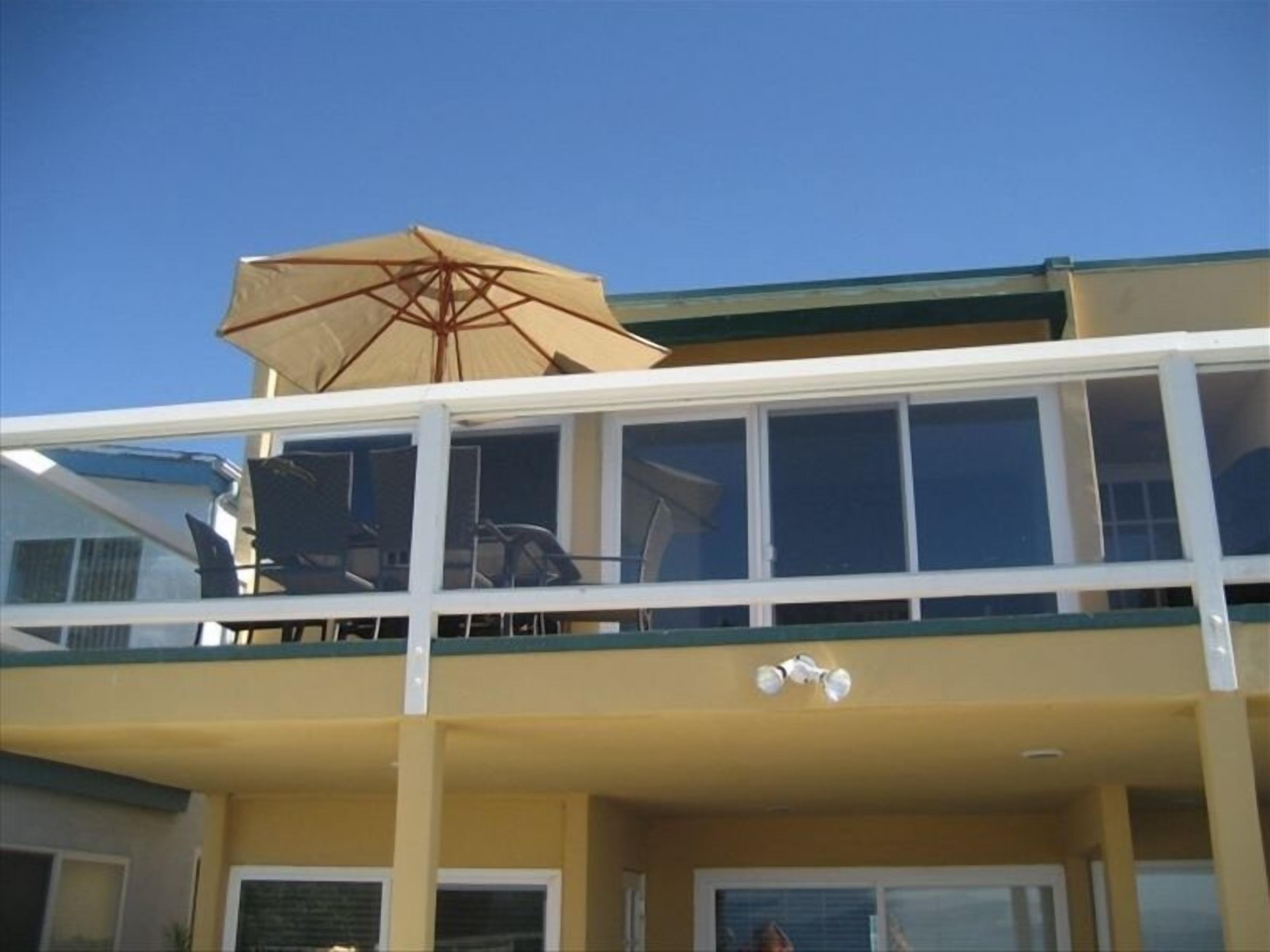 Ein zweistöckiges Gebäude mit Balkon, Deckenventilator und großem Sonnenschirm.