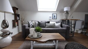 A modern living room with a skylight, grey sofa, wooden coffee table, and a bookshelf. - Charming Modern cosy Cottage -50m2- (Bourbourg)