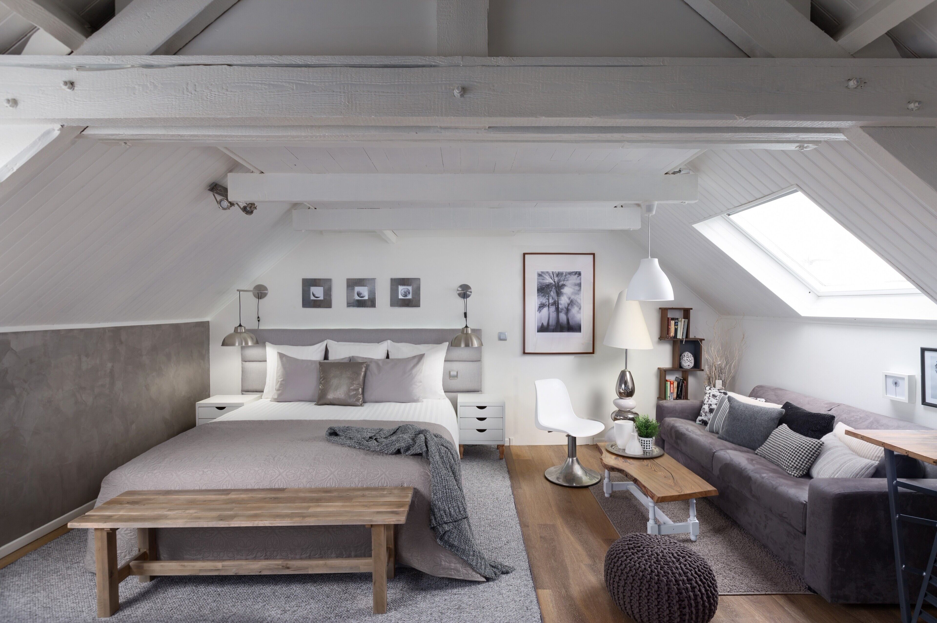 A modern loft bedroom with a large bed, a desk, and a sofa.