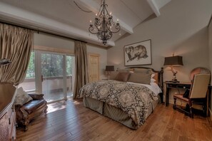 Un dormitorio amplio con una cama grande, una araña de cristal, un escritorio con lámpara y una silla.