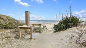 Un banco de madera y una estructura de madera en una playa arenosa con cielo despejado.