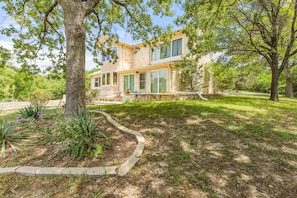 A two-story house with a stone facade, large windows, and a well-maintained lawn.