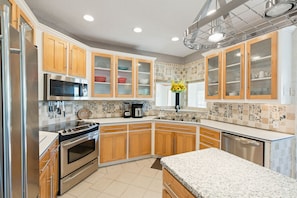 A kitchen with wooden cabinets, stainless steel appliances, and a tiled backsplash.