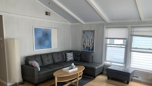 A modern living room with a sectional sofa, a coffee table, and a painting of sailboats.