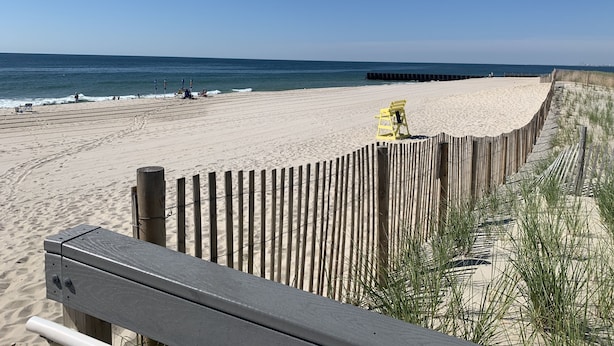 A beach with a wooden fence and a lifeguard chair.