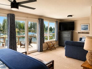 A room with a view of a marina, a ceiling fan, a television, and a sofa.