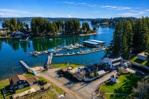 A marina with docked boats, a small building, and a house with a garage.