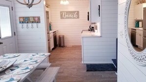 Eine Küche mit weißen Schränken, einer Kaffeemaschine und einem Schild mit der Aufschrift 'Meet me at the Beach'.