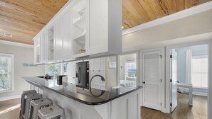Una cocina moderna con una isla central, taburetes de bar y vistas al exterior.