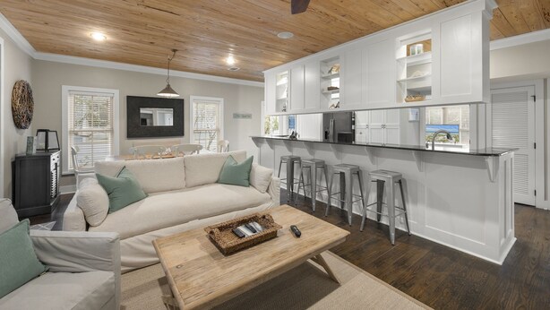 Una cocina moderna con armarios blancos, una isla central con taburetes y un ventilador de techo.