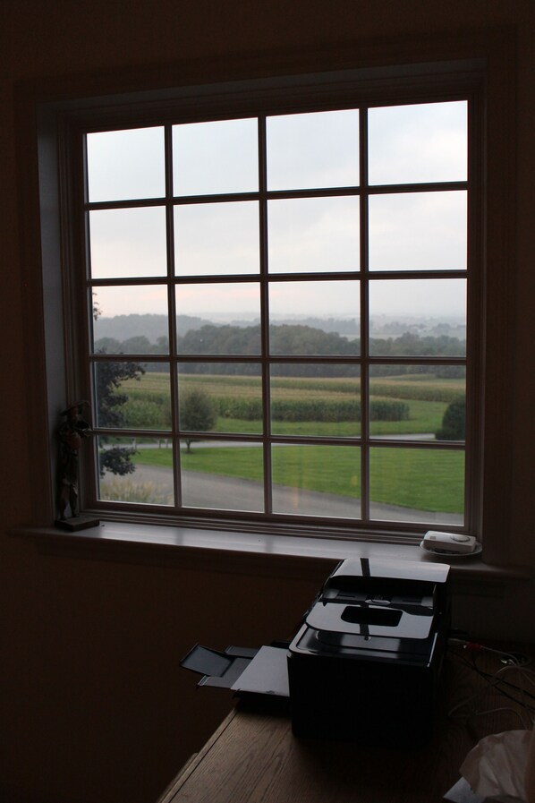 A room with a large window overlooking a green landscape. A printer is on the windowsill.