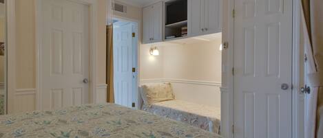 A bedroom with a bed, a closet, and a small shelf unit.