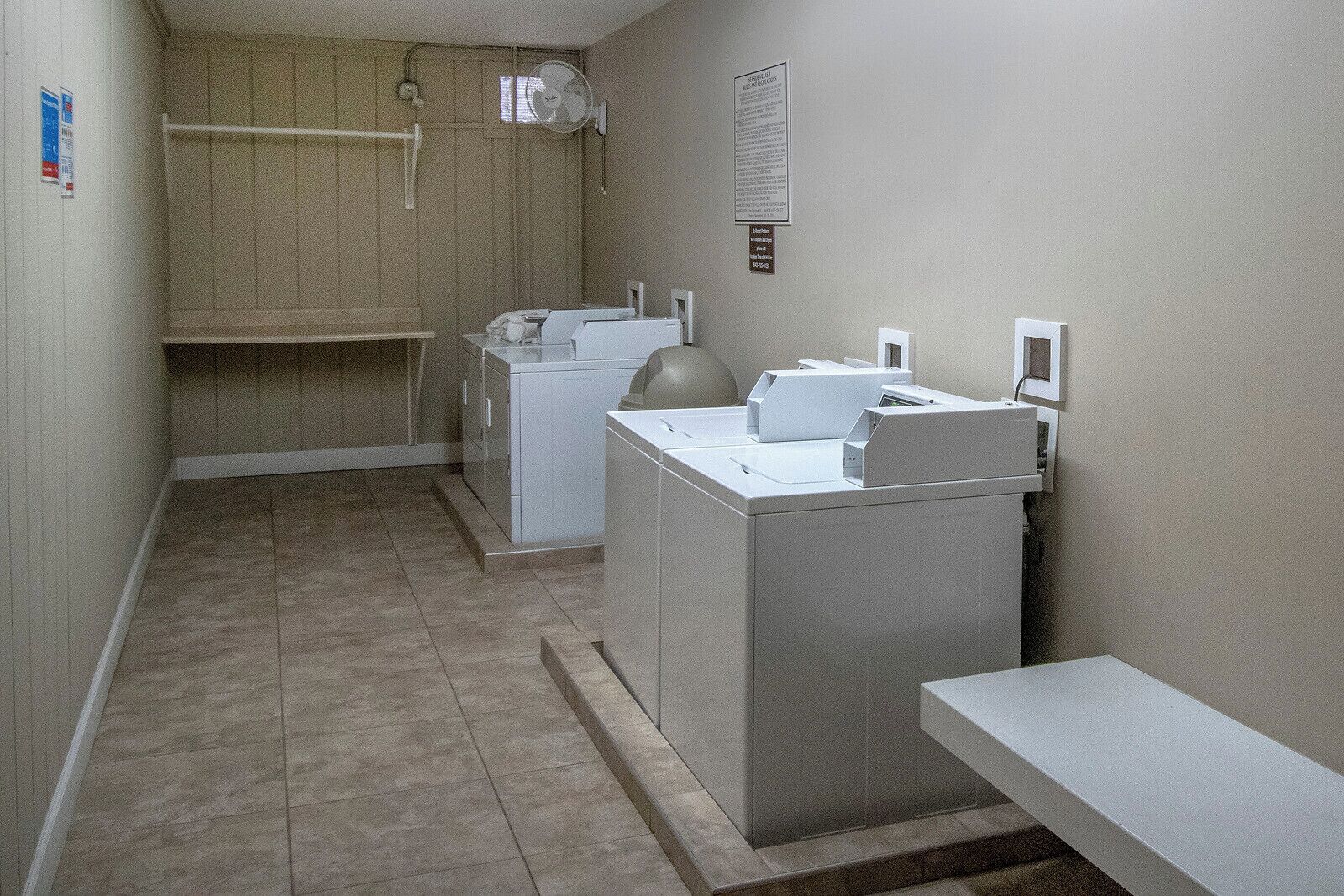 A laundry room with a washing machine, dryer, and a small table.