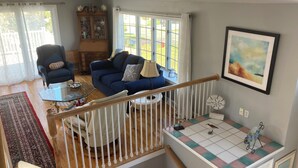 Un salon avec un canapé bleu, un meuble en bois et un escalier doté d’une rampe.