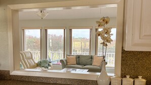 A kitchen with a built-in window seat overlooking a balcony, a white vase with an orchid, and three white containers labeled sugar, coffee, and tea.