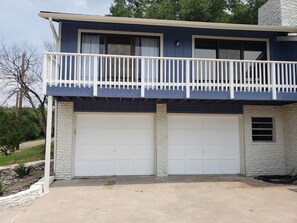 Une maison à deux étages avec un balcon, deux garages et une façade en pierre.