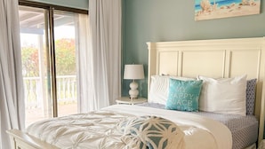 A bedroom with a bed, a nightstand, a lamp, a painting, and a view of the outdoors.