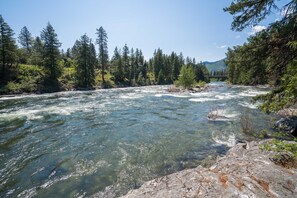 A river flowing through a forested area with a bridge in the background. - Beautiful Riverfront Home-Quiet and Private-Leavenworth-Family Friendly-WI-FI (Leavenworth)