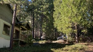 Una cabaña con balcón, rodeada de un bosque denso.
