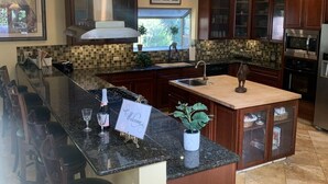 Una cocina con armarios de madera oscura, una isla grande con un fregadero y una campana extractora de acero inoxidable.