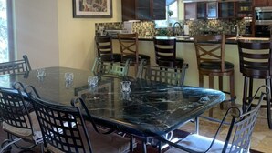 Una cocina moderna con armarios de madera oscura, una mesa de comedor con superficie de vidrio y un ventanal grande.