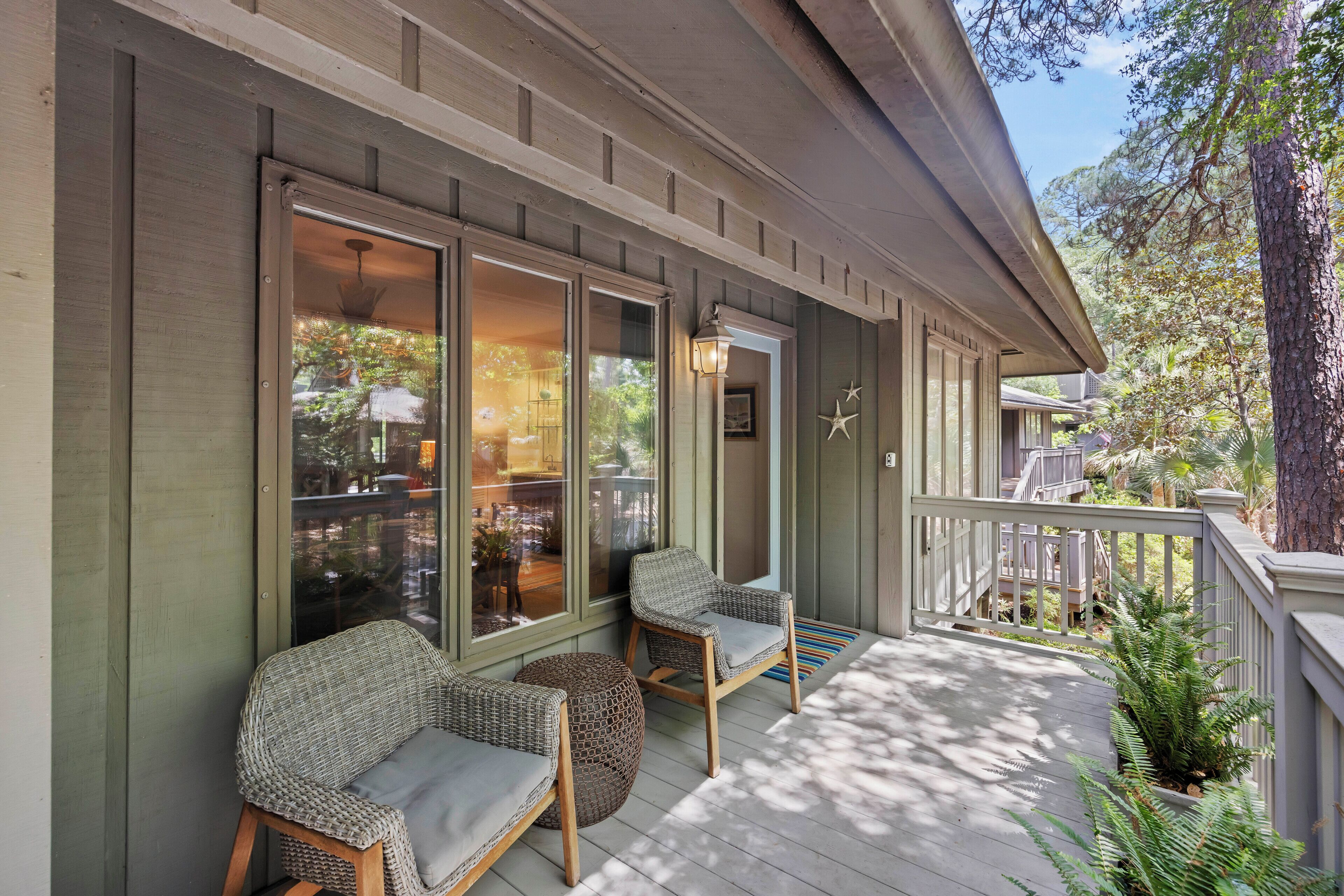 A covered porch with wicker furniture, a railing, and a view of the outdoors.