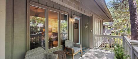 A covered porch with wicker furniture, a railing, and a view of the outdoors.