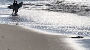 A beach scene with two people carrying surfboards. - PERFECT, BEAUTIFULLY NEWLY DESIGNED 1,000 FT. MONTAUK OCEANFRT 3-LEVEL TOWNHOUSE (Montauk)