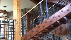 A wooden staircase with metal railings in a building with stone walls and a wooden ceiling.