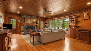 A cozy living room with a fireplace, a sofa, a television, and a bookshelf. - Lake Summit Estate.  Directly On The Water! (Zirconia)