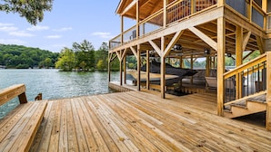 A wooden deck with a covered seating area and a view of a lake. - Lake Summit Estate.  Directly On The Water! (Zirconia)