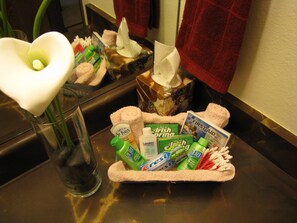 A bathroom counter with toiletries, a tissue box, and a vase with a white flower. - Near Anchorage Airport, Lake Hood and the Cook Inlet Coast (Anchorage)