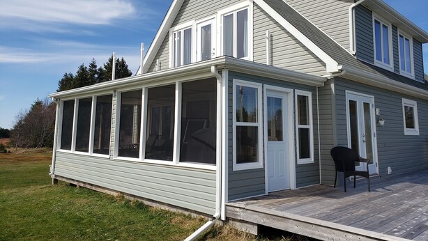 Ein Haus mit überdachter Veranda, großen Fenstern und einem Satteldach.