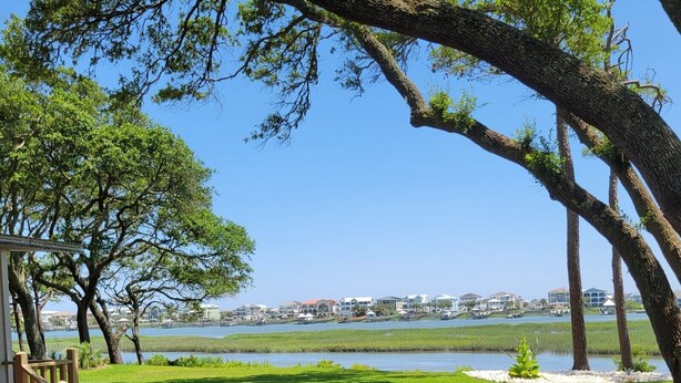 A patio area with wicker chairs and a small table, overlooking a body of water and a marina with boats. - Breathtaking Waterway Views. 1BR. 1Bath. Kitchen. Porch. 2 Person. 5 Star Views (Ocean Isle Beach)